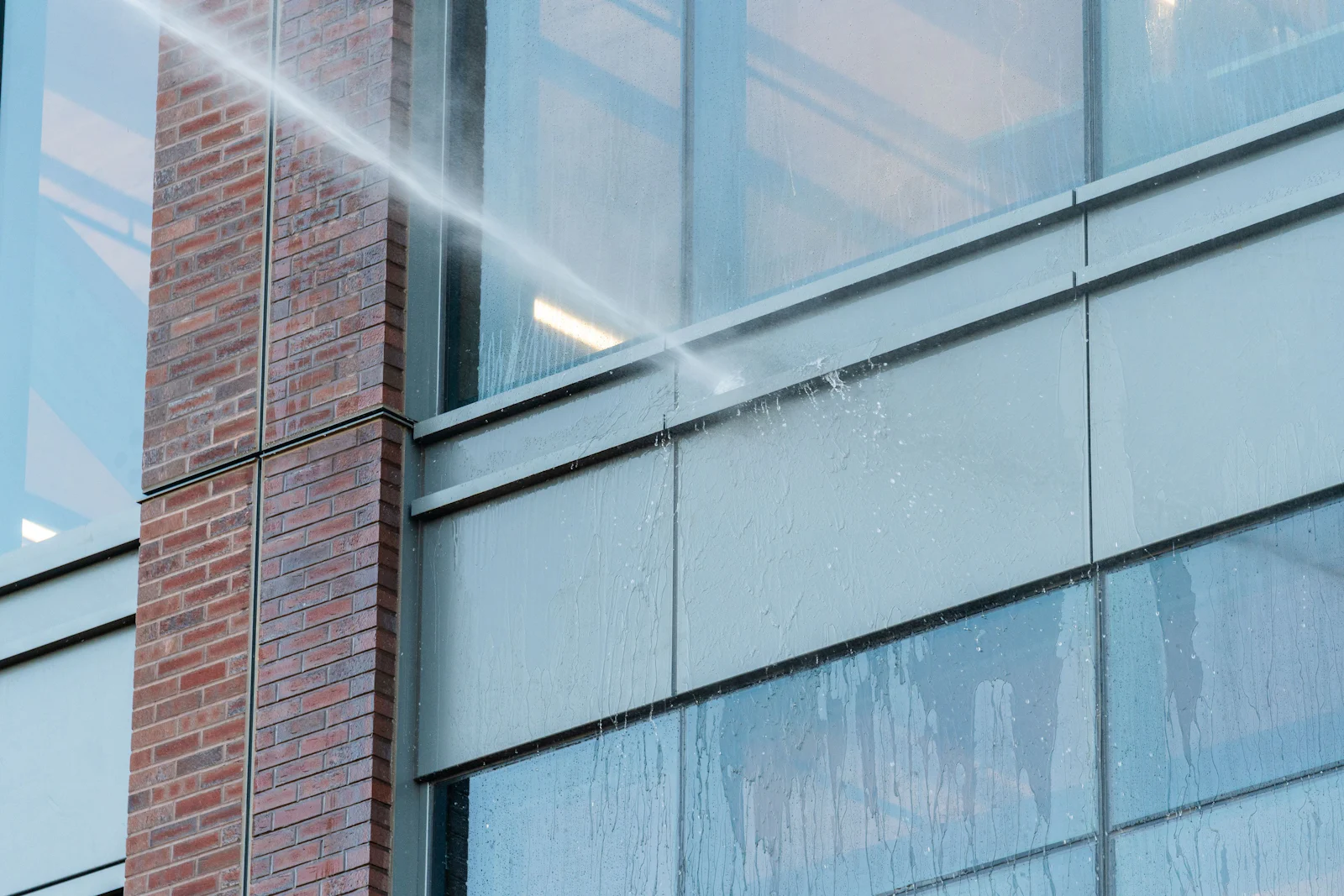 Cleaning solution being sprayed onto a brick and glass building exterior